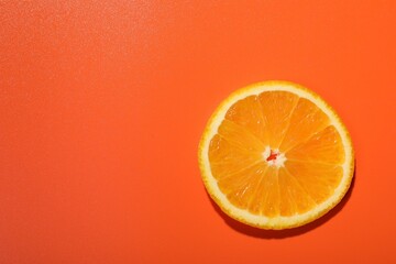 Slice of juicy orange on terracotta background, top view. Space for text