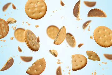 Tasty dry crackers falling on light blue background