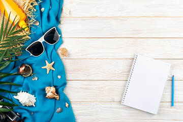 Vacation planning background of notebook seashells, starfish, sunglasses, compass, camera and straw...