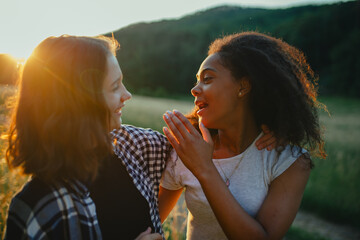 Young teenager girl best friends spending time in nature, during sunset. Girls on walk, embracing.