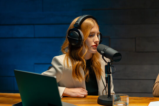 A woman with headphones in front of a microphone. At podcast studio