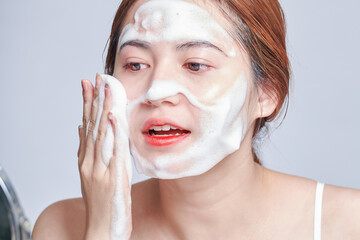 Smiling young woman washing foam face by natural foamy gel. satisfied girl with bare shoulders...