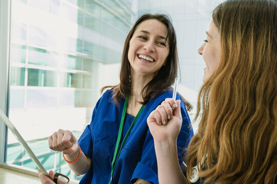 Smiling nurse holding tablet PC and talking to doctor in hospital