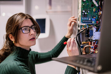Engineer looking at laptop and fixing network server in office