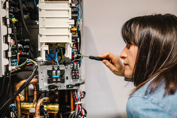 Focused female technician repairing AC unit