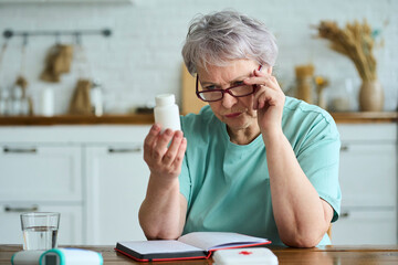 Senior woman analyzing medicine bottle at home