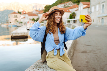Young female tourist is exploring new city making photo on smartphone. Selfie time. Lifestyle,...