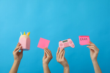 Stationery and exam record, in hands on a blue background.