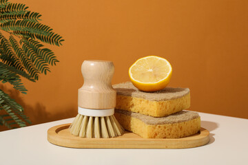 Sponges, brush and lemon on brown background