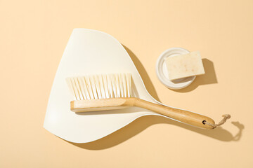 Soap and brush with scoop on beige background, top view