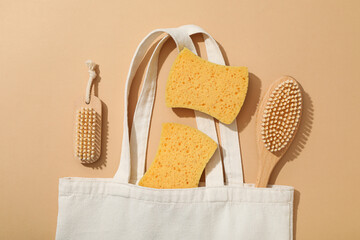 Brushes and sponges in cotton bag on beige background, top view
