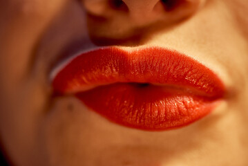 Close-up of a girl with red painted lips, passionately biting her lips.