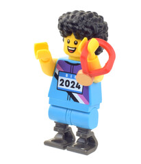 Fototapeta premium Lego minifigure of disabled person winner a gold medal or price in the running isolated on white. Editorial illustrative image of popular children plastic toy.