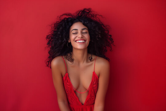 woman in studio, full body, wearing red dress trand up front of camera smiling having curly black hair beautiful smile photo showing full body on solid isolated red backround, studio light