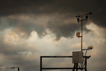 Image of anemometer on roof top weather station with storm clouds on summer tropical twilight sky. Image use for meteorology forecast and presentation background.