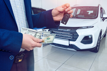 Person holding dollar money in the hands stands front car at modern showroom