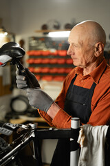 Bike service, repair and upgrade concept. Cycling mechanic fixing bicycle seat in workshop or...