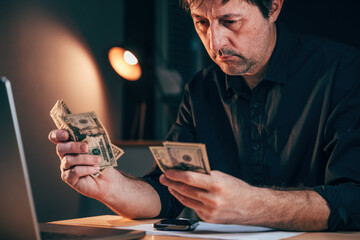 Businessman counting american dollars at office desk