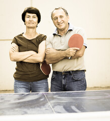 Portrait of elderly couple with rackets for table tennis