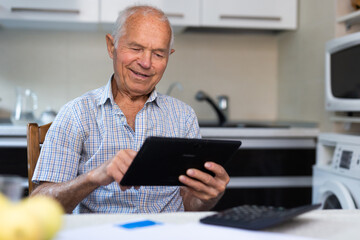 Senior man with tablet making purchases at home