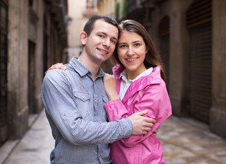 Young couple guy and girl hugging walking along streets of european city