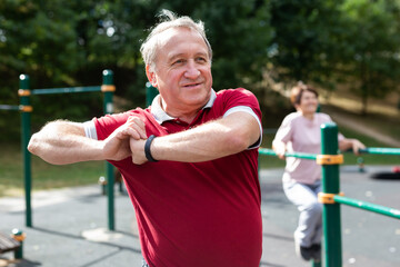 Elderly man doing gymnastics on an outdoor sports ground