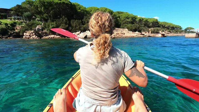 Back view of excited woman tourist inside a kayak canoe with coastline and islands in background enjoying and having fun in travel summer holiday vacation. Happy people tourism. Outdoor leisure lady