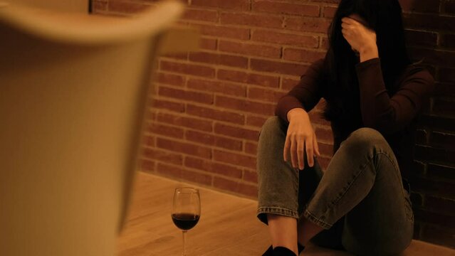 Sad desperate woman sitting on the floor alone at home thoughtful about breakup relationship or life drama. Depression alcohol Upset adult female cry desperate sitting on the floor in loneliness