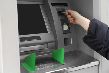 Woman inserting credit card into cash machine outdoors, closeup