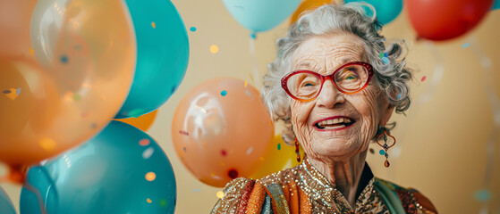 Elderly woman in a glittering evening dress, smiling as multicolored balloons pop around her, on a cream background