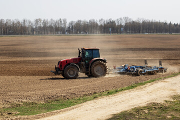 Fototapeta premium Red tractor is plowing a field closeup