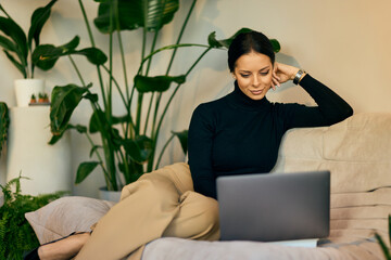 Businesswoman working over the laptop, sitting on the couch. - 785106460