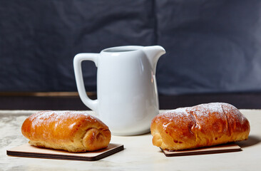 Homemade buns with jam with powdered sugar on wooden background. Fresh bakery and milk jug on...