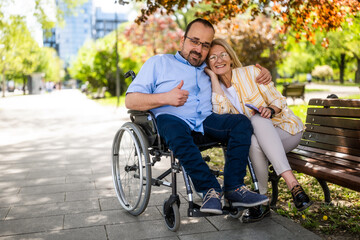 Man in wheelchair is spending time with his mother in park. - 785111295