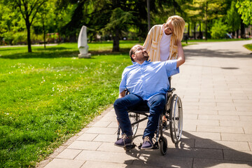 Man in wheelchair is spending time with his mother in park. They are enjoying sunny day together. - 785111487