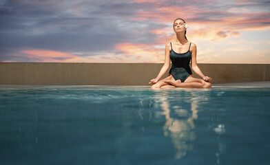 Wellness spa, vacation and yoga meditation concept. Pretty young woman in swimsuit sitting in lotus...