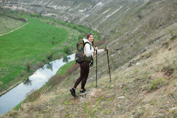 European beautiful girl is hiking in the mountains. White woman travels with backpack in nature.