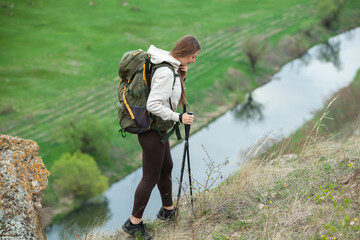 European beautiful girl is hiking in the mountains. White woman travels with backpack in nature.