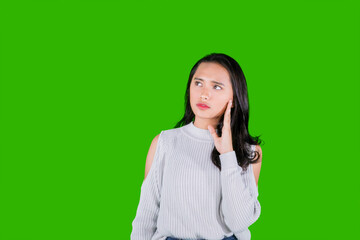 Beautiful young Asian woman thinking isolated over green background