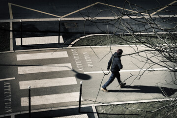 Street photography with a man walking downtown on the crosswalk in Paris, France