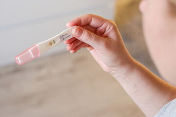 Close up top view of a woman holding a positive pregnancy test