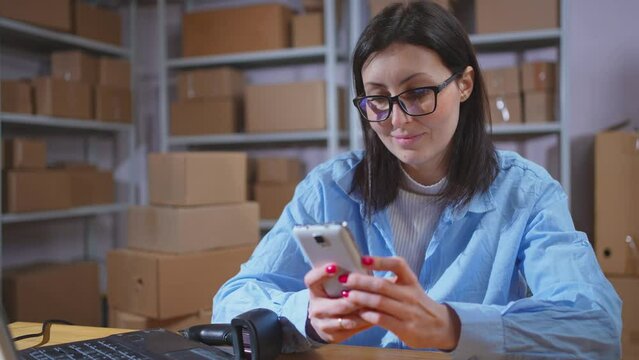 portrait of a positive young female startup employee with a phone in her hands smiling close up