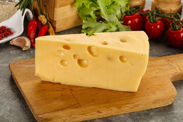 Swiss Maasdam cheese triangle over board