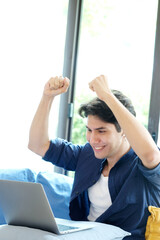 Happy young man arms up while working with laptop computer at home, Positive emotion when working at home
