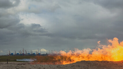 Fototapeta premium Development of gas wells in the northern gas field. Flaring of contaminated gas during bottom-hole cleaning of the pay zone. Flow of gas from the well under high pressure. Beautiful orange flame