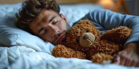 A tired handsome man in pajamas lies in bed with a teddy bear.