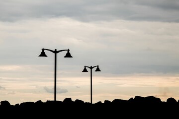 Obraz premium Silhouette shot of a street lights on the cliff
