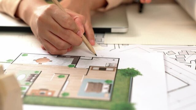 Professional engineer team discussion about house design on meeting table with architectural equipment and building blueprint scatter around at modern office. Focus on hand. Closeup. Delineation.