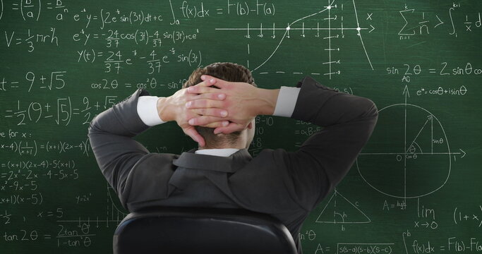 Image of Caucasian man sitting in front of chalkboard with moving mathematical graphs and formulae w