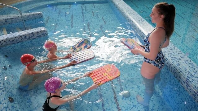 Three children learn to swim and dive in the pool together with a coach. Group of children on a swimming class. 